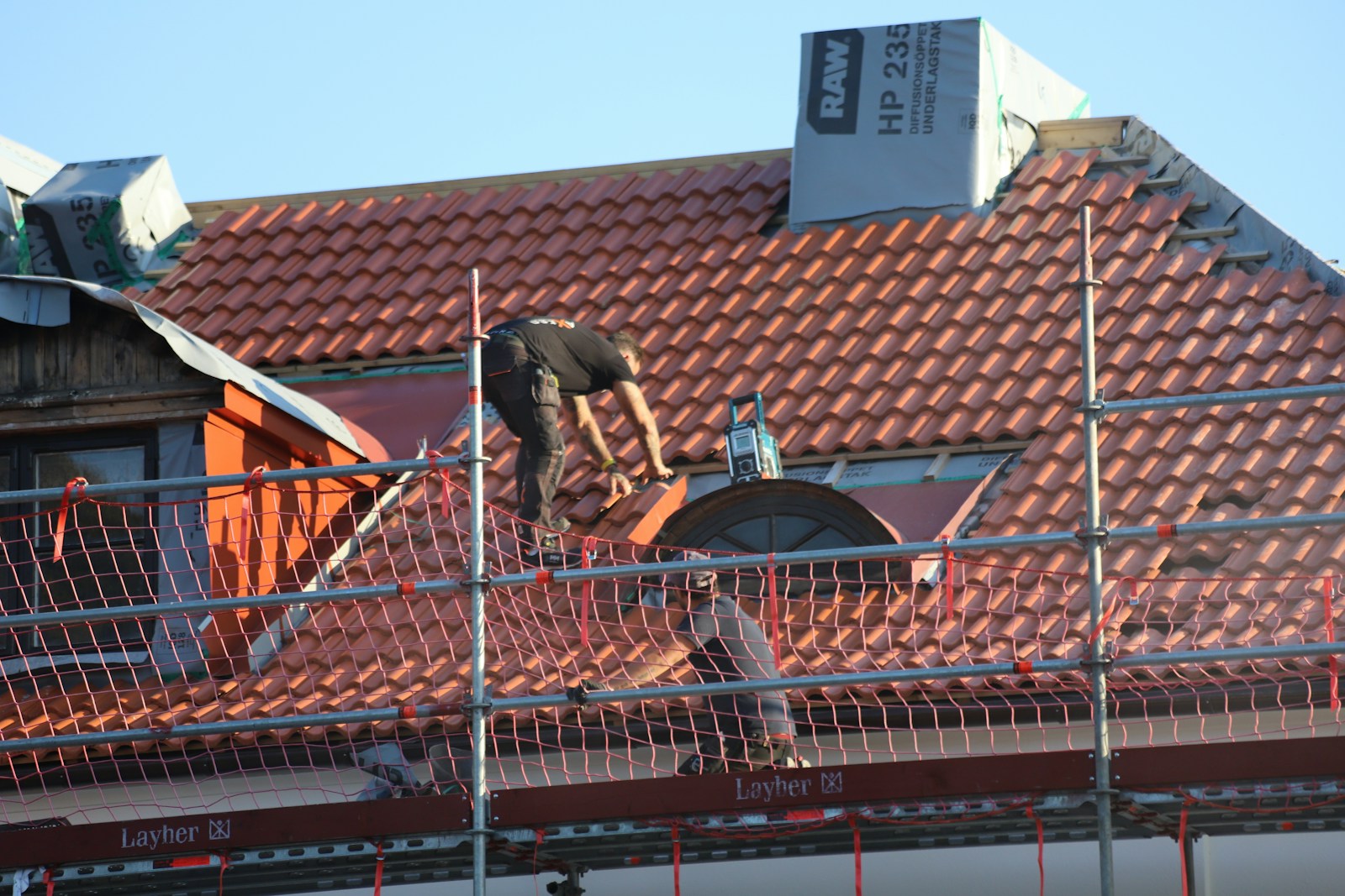 Couvreur travaillant sur une toiture en tuiles rouges